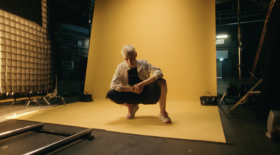 a man kneeling down in front of a yellow wall