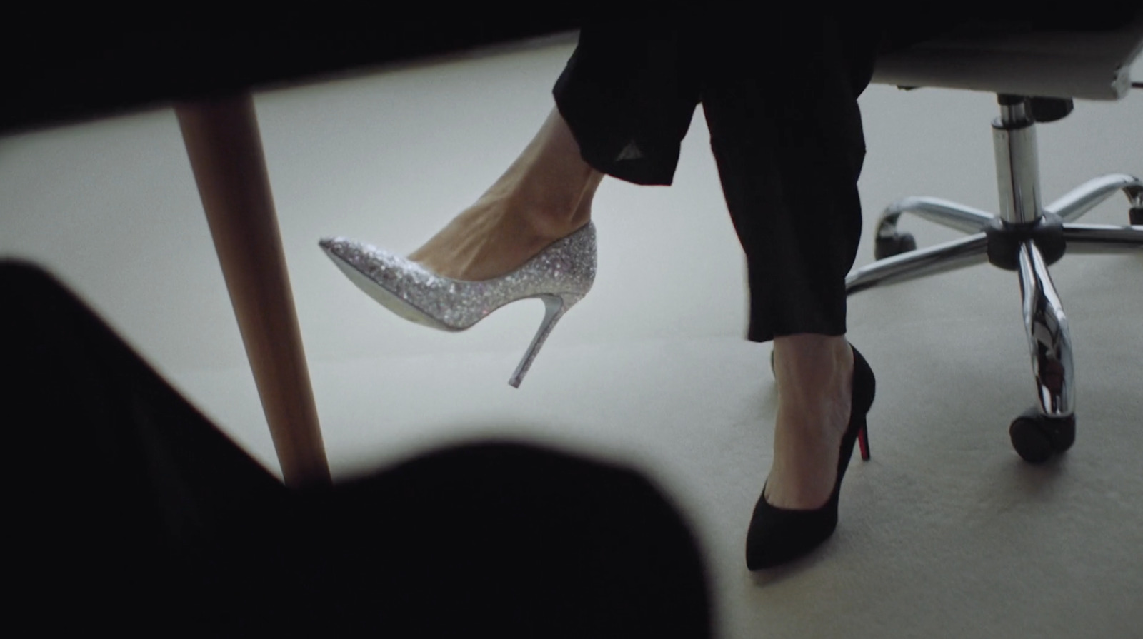 a woman's feet in high heels sitting on a chair