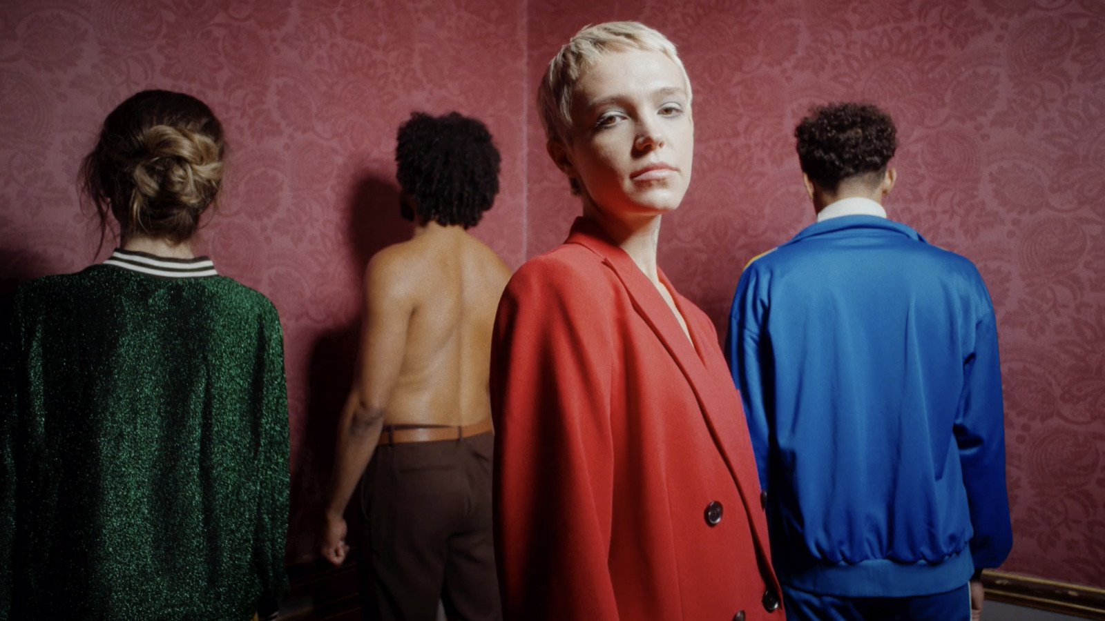 a group of people standing in front of a red wall