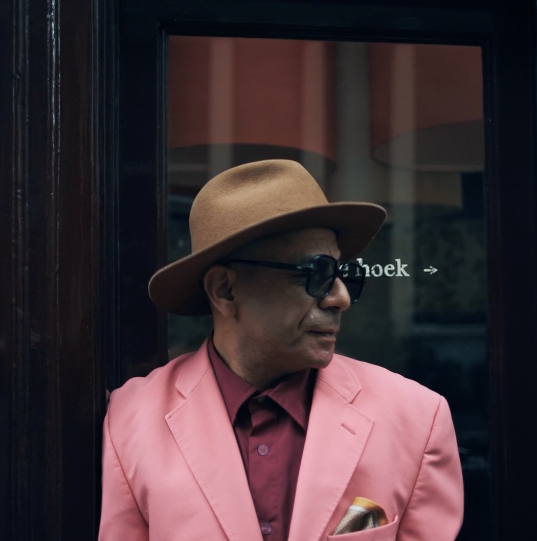 a man wearing a pink suit and a brown hat