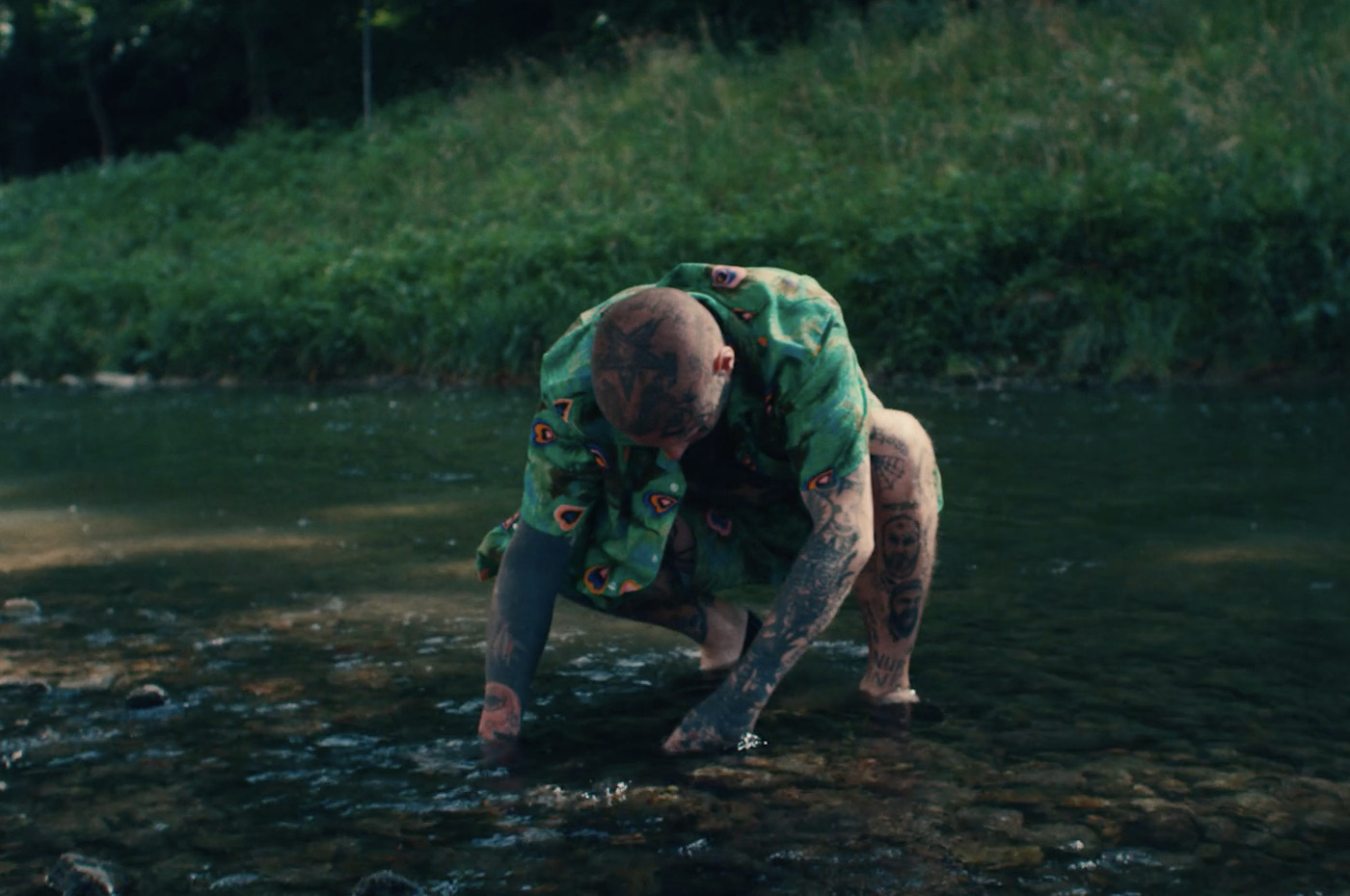 a man in a green shirt standing in a river