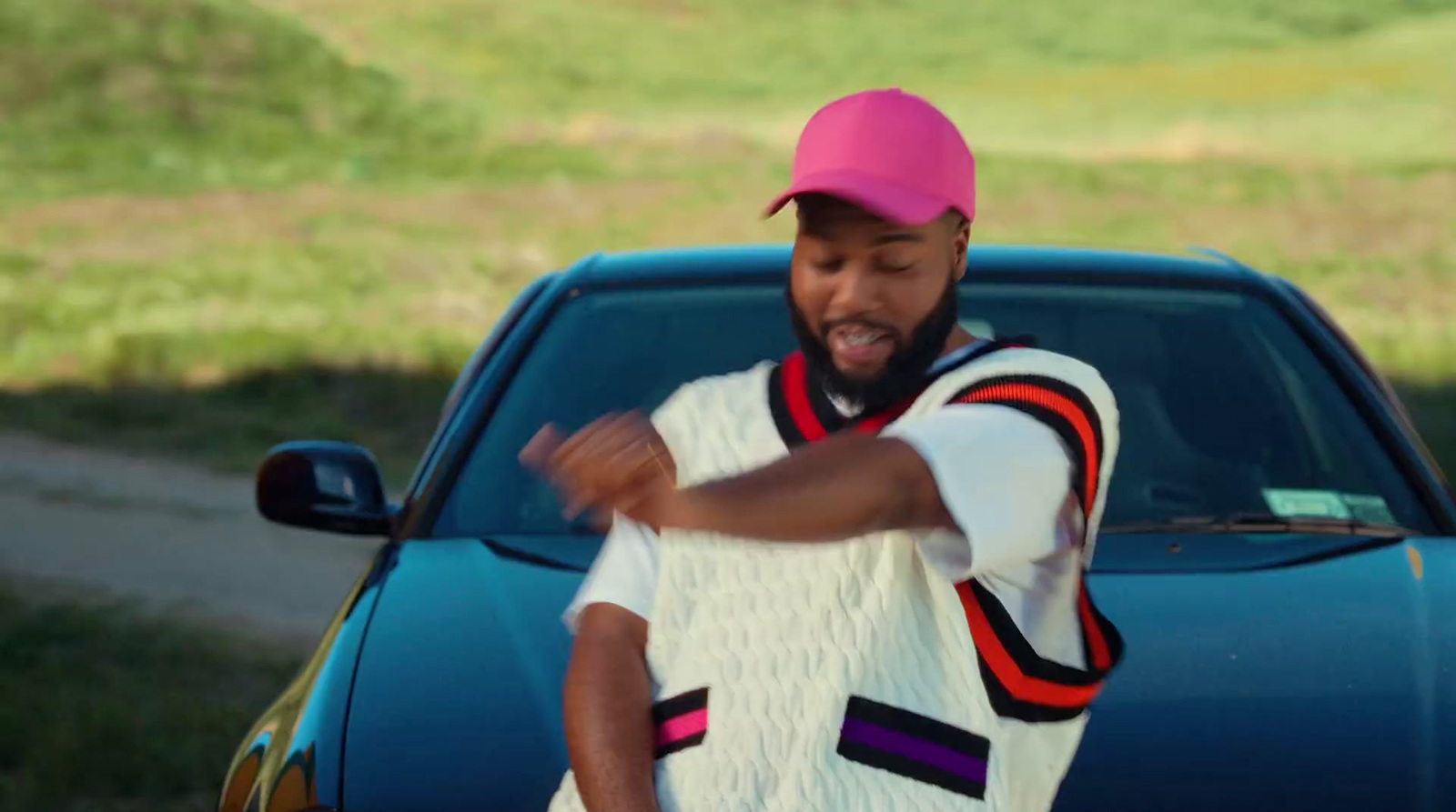 a man in a pink hat standing next to a blue car