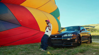 a man standing next to a car in front of a hot air balloon