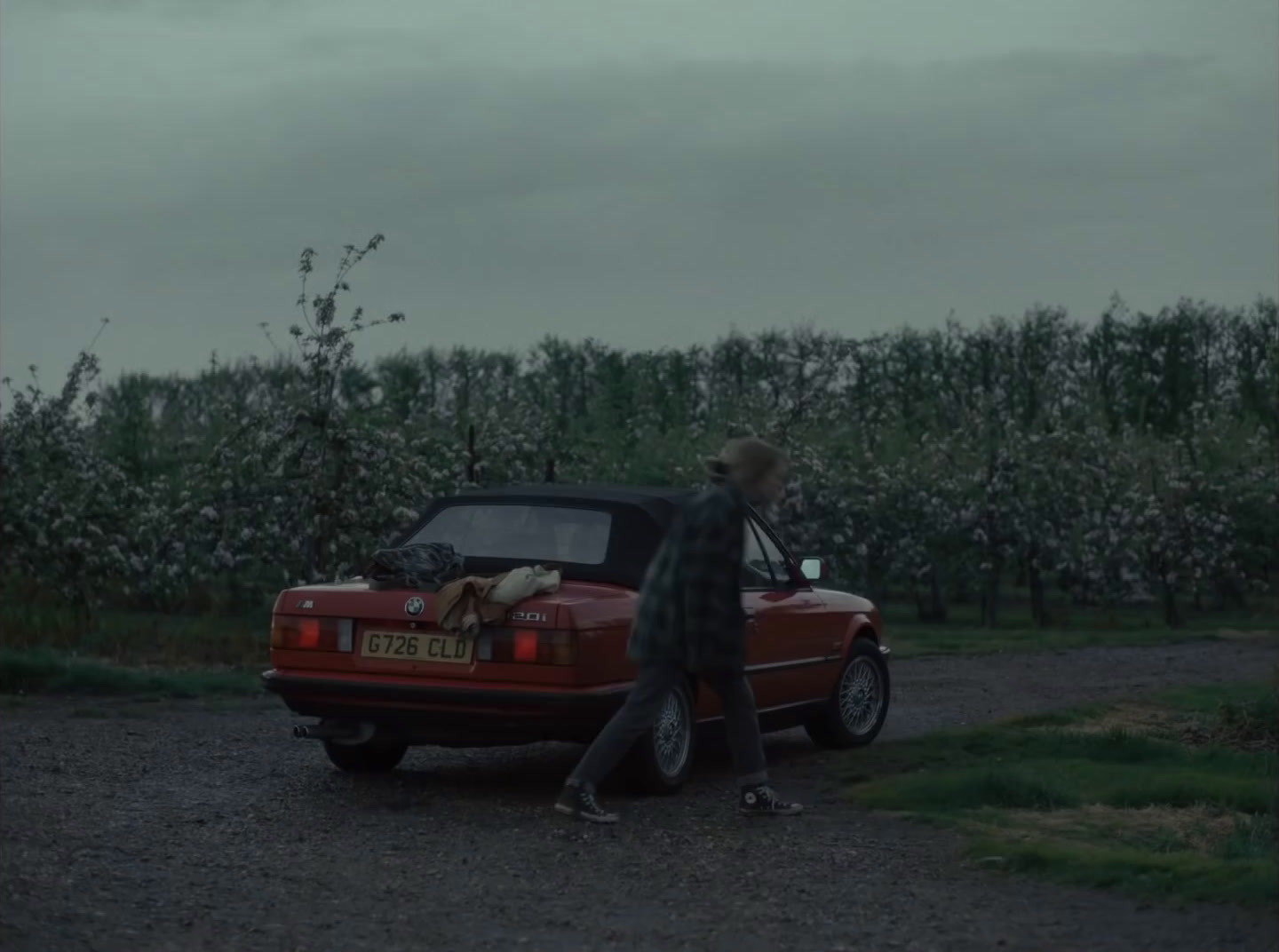 a person walking towards a red car in a field