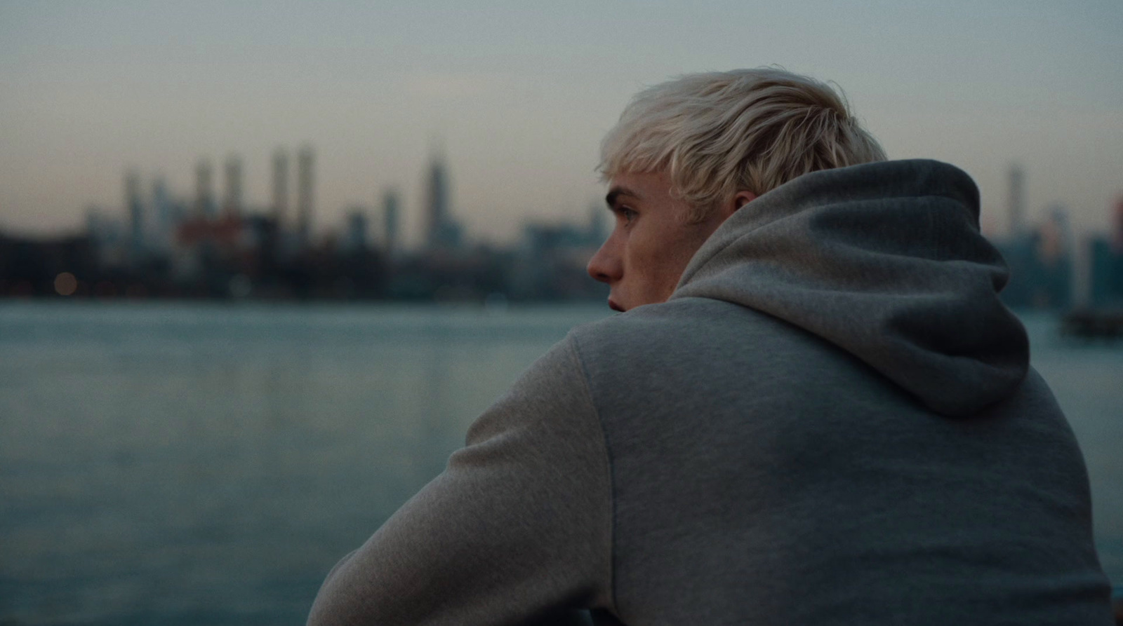 a man in a hoodie looking out over a body of water