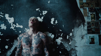 a man with tattoos standing in front of a wall