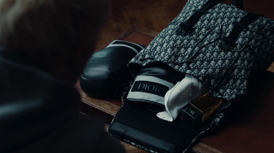 a person sitting on a bench with a handbag and a pair of black shoes