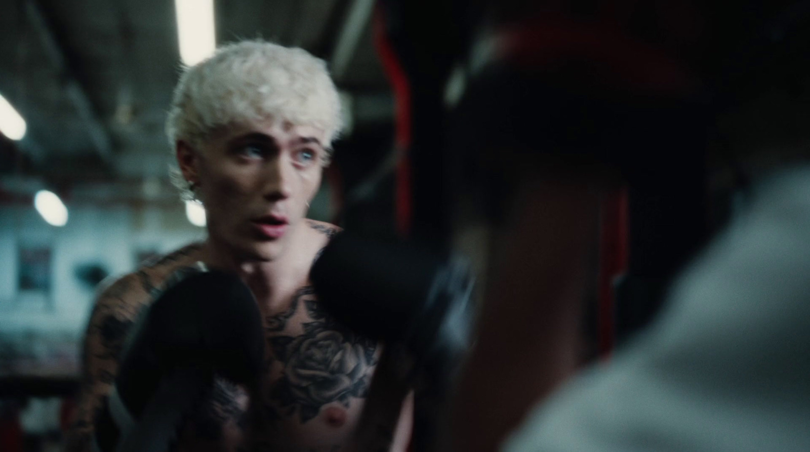 a man with white hair and tattoos standing in a gym