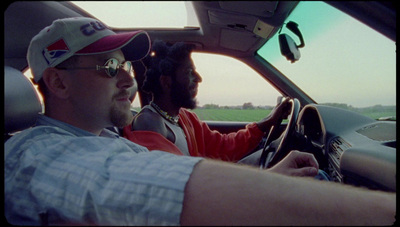 a man driving a car with another man in the passenger seat