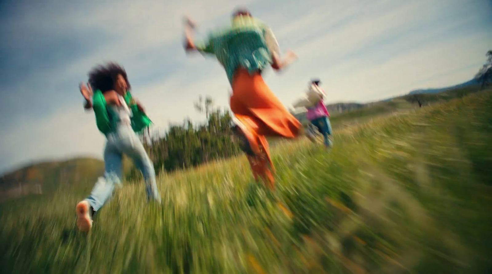 a group of people running through a grass covered field