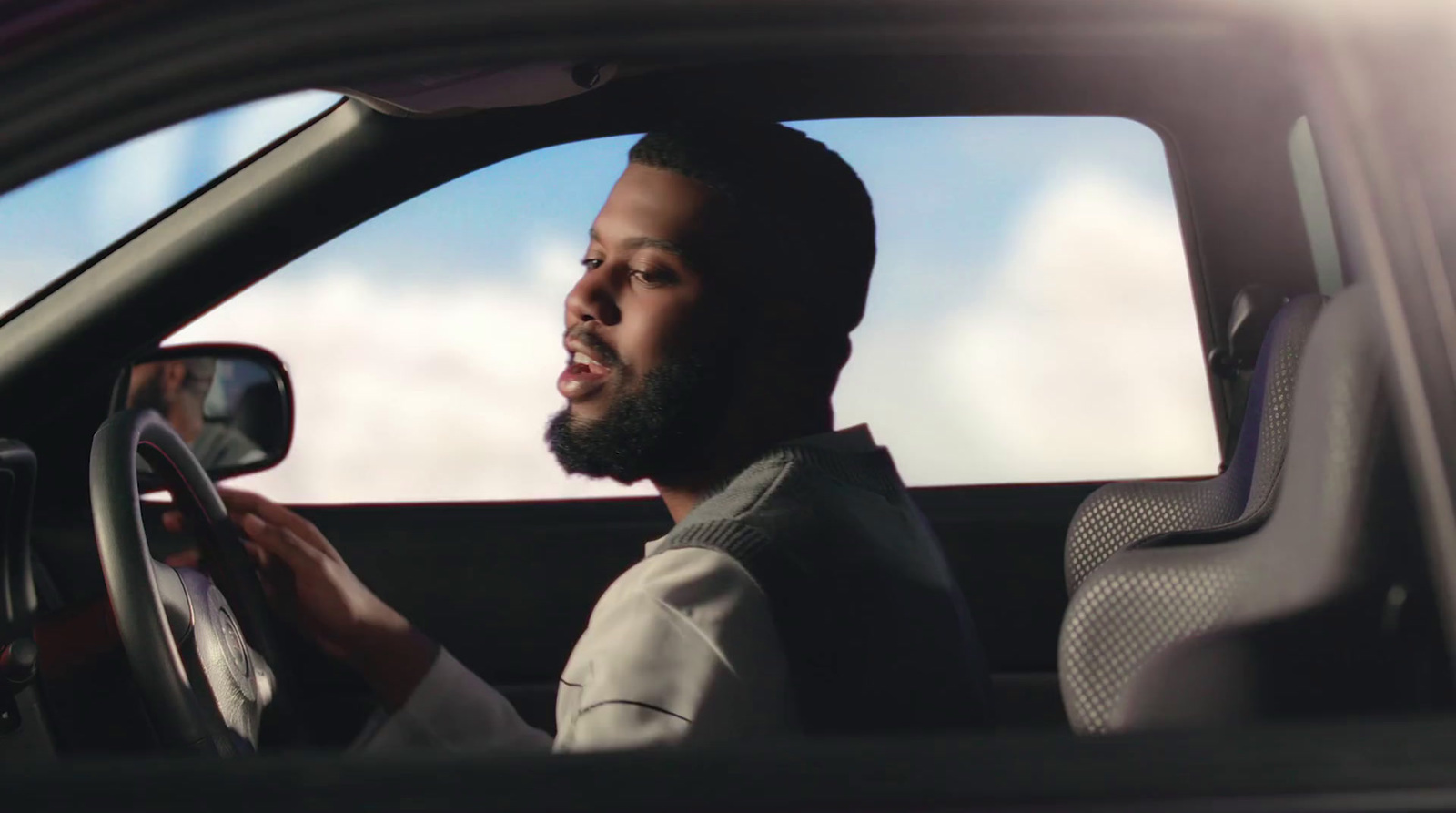 a man sitting in a car holding a steering wheel