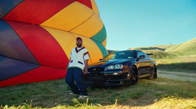 a man standing next to a car in front of a hot air balloon