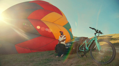 a man standing next to a bike next to a hot air balloon