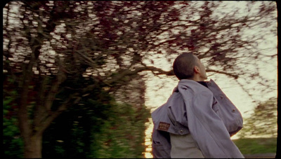 a man walking down a street next to a tree