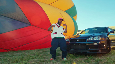 a man standing next to a car in front of a hot air balloon