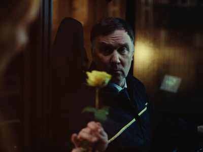 a man holding a yellow rose in his hand