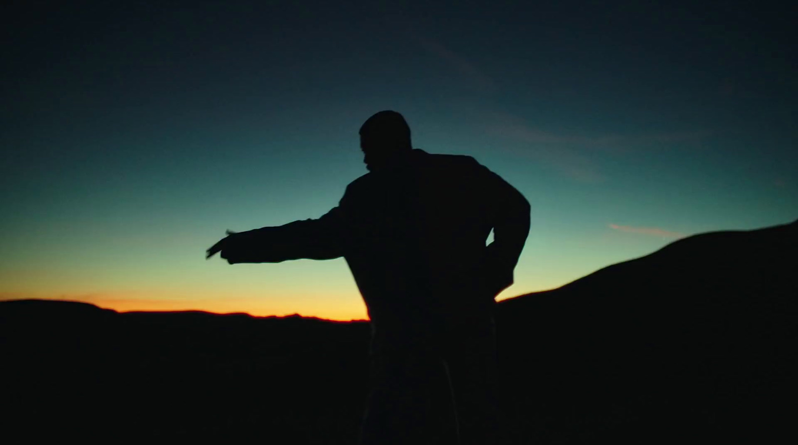 a silhouette of a man holding a frisbee at sunset