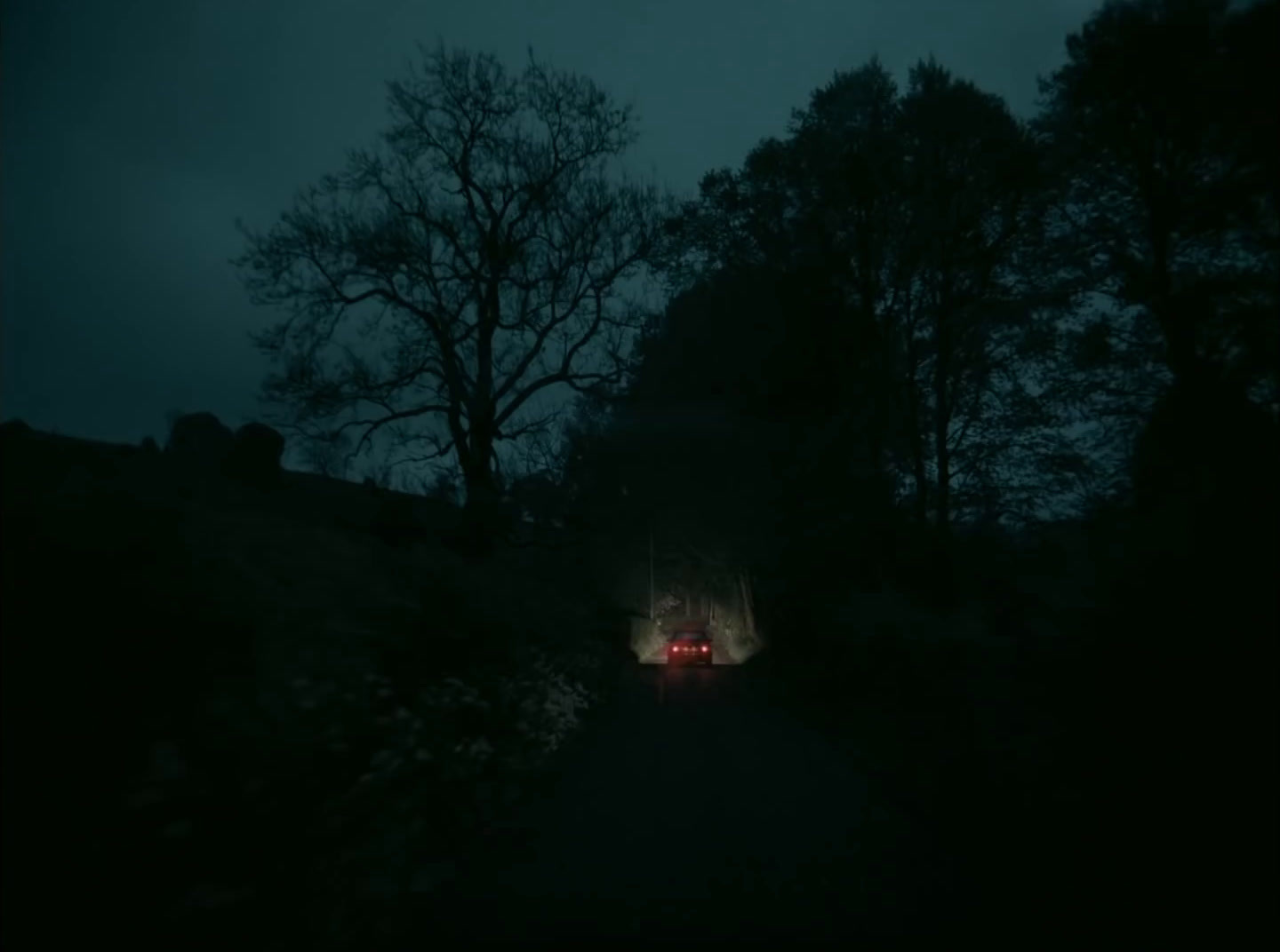 a car driving down a dark road at night