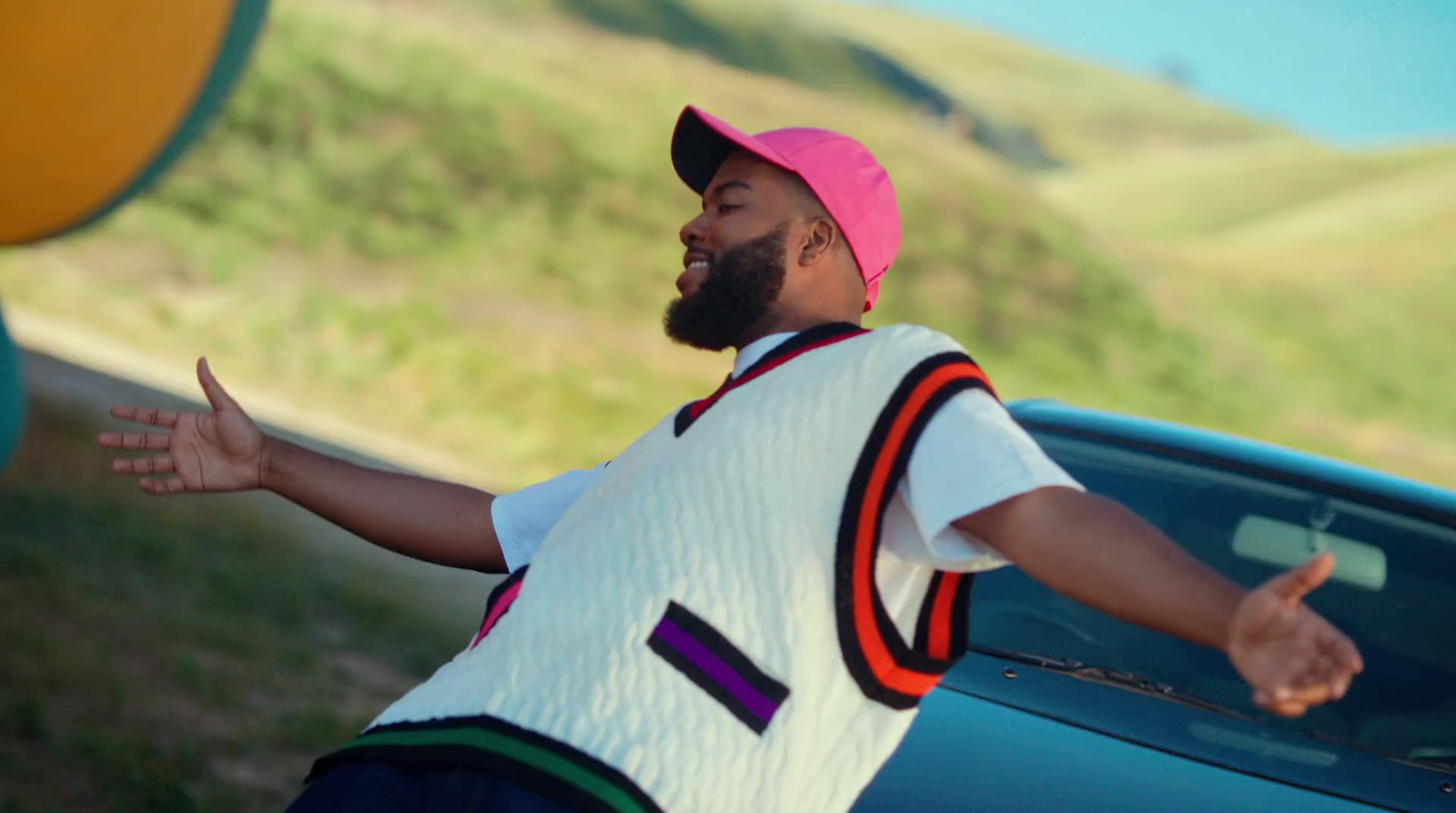 a man in a pink hat leaning on a car