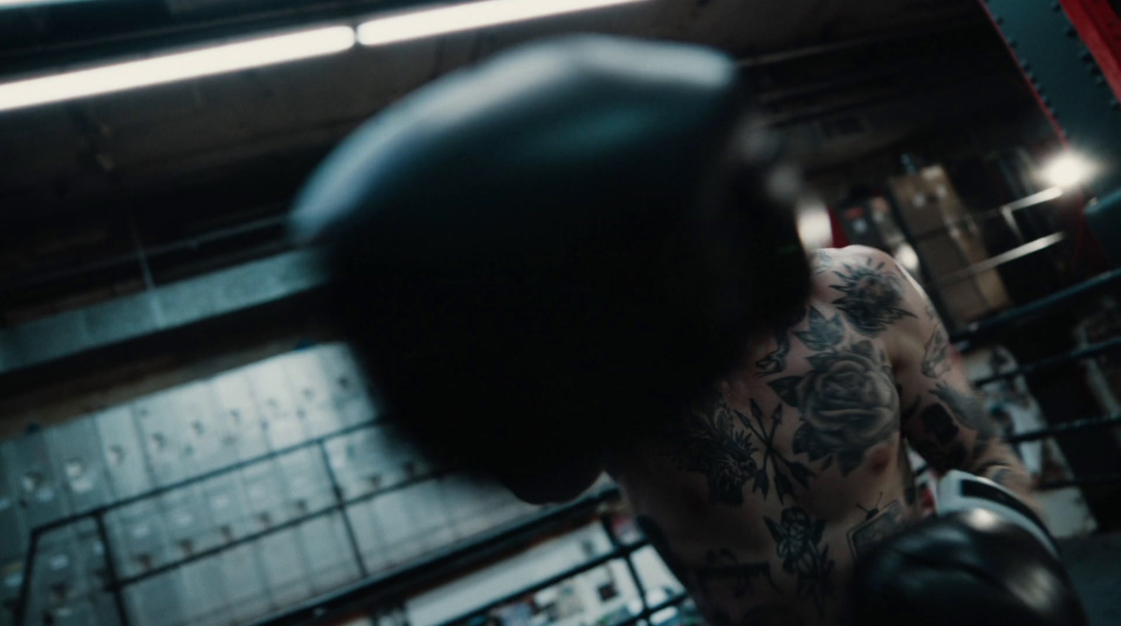 a man with a tattoo on his arm wearing boxing gloves