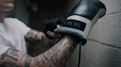 a man with a tattoo on his arm holding a pair of gloves