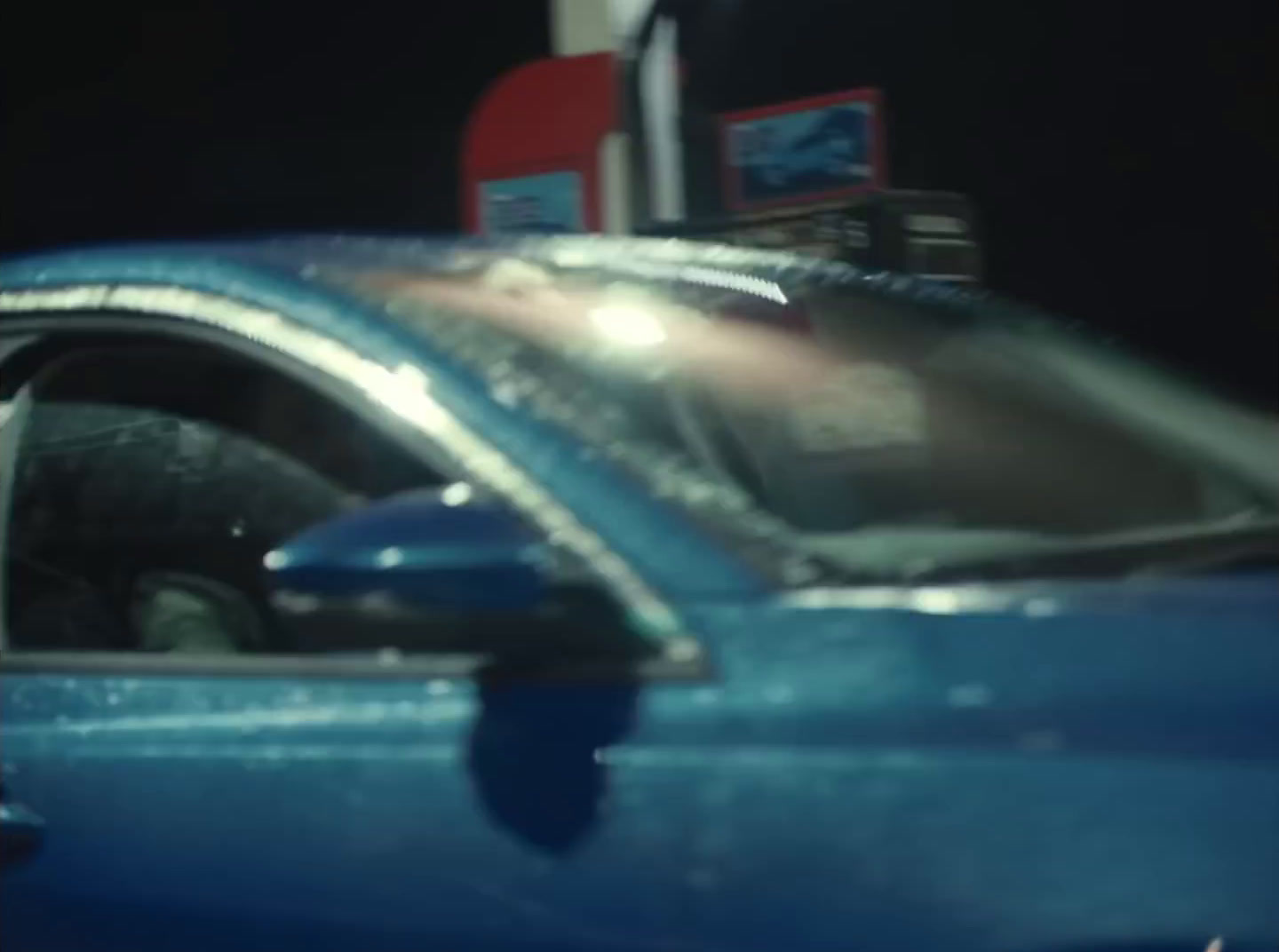 a blue car parked in front of a gas station