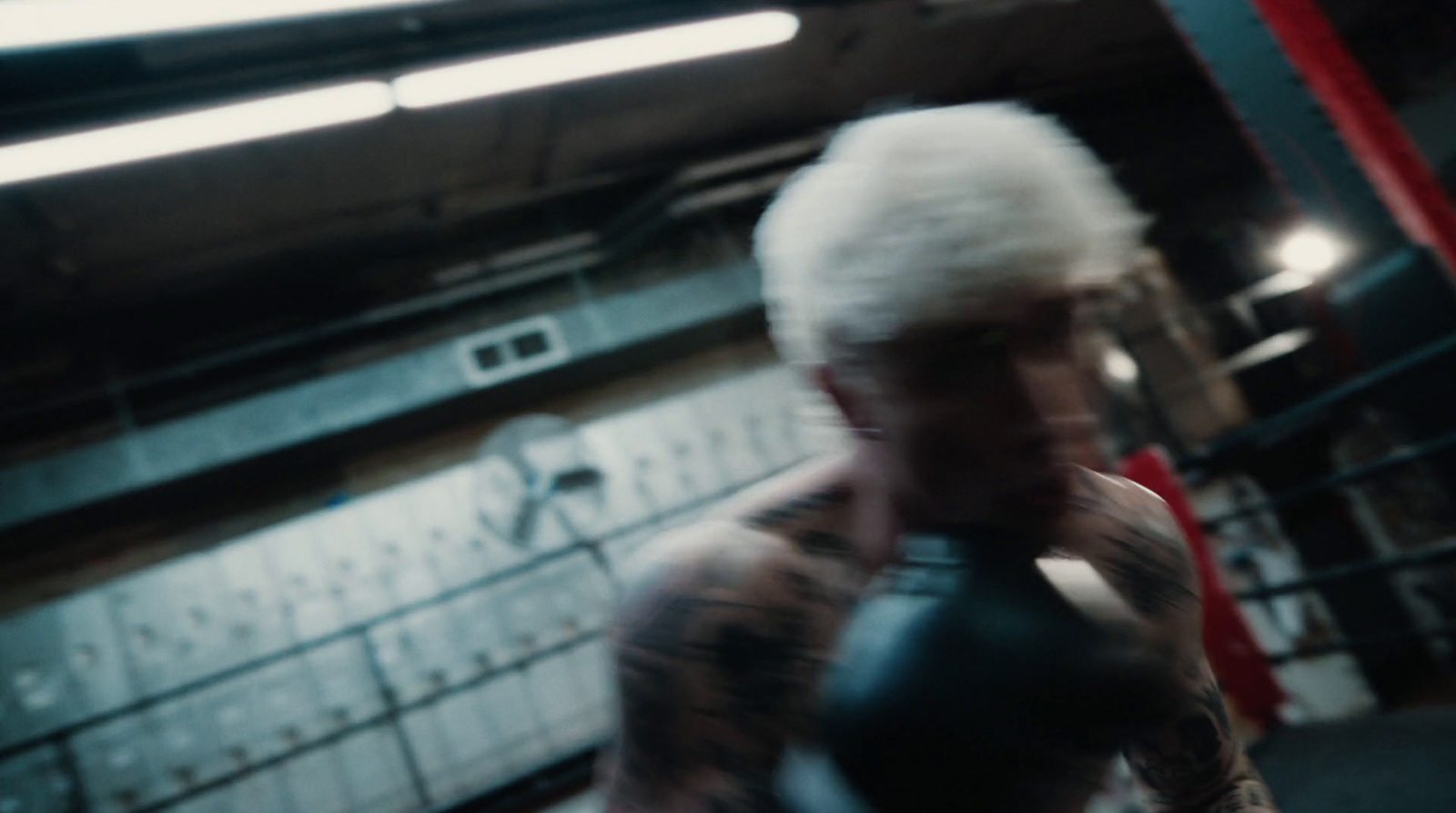 a man with white hair is boxing in a gym