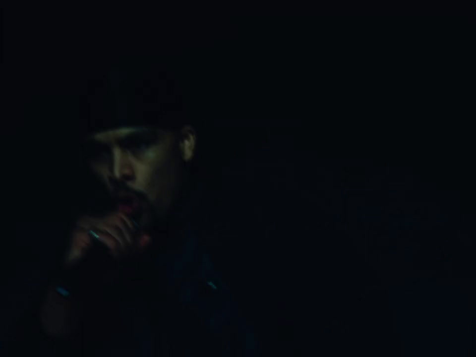 a man in a dark room with his hand on his mouth