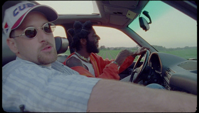 a man driving a car with another man in the passenger seat