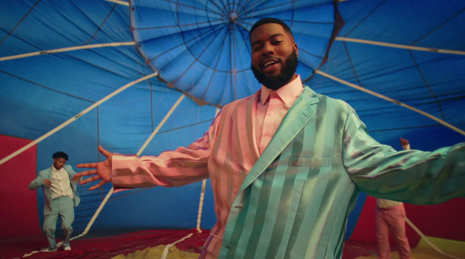 a man standing in front of a blue and red hot air balloon