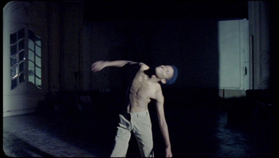 a shirtless man standing in a dark room