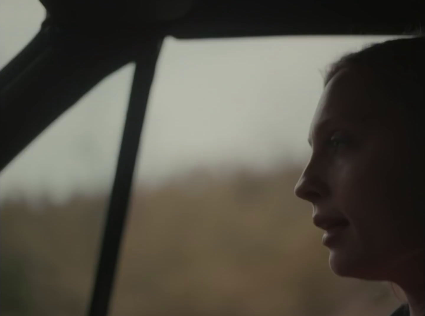 a woman sitting in a car looking out the window