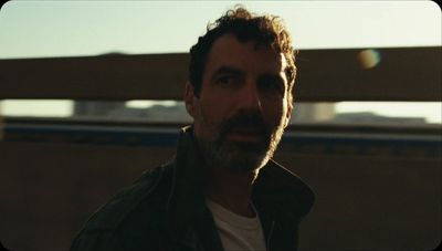 a man with a beard standing in front of a fence