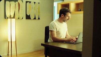 a man sitting at a desk using a laptop computer