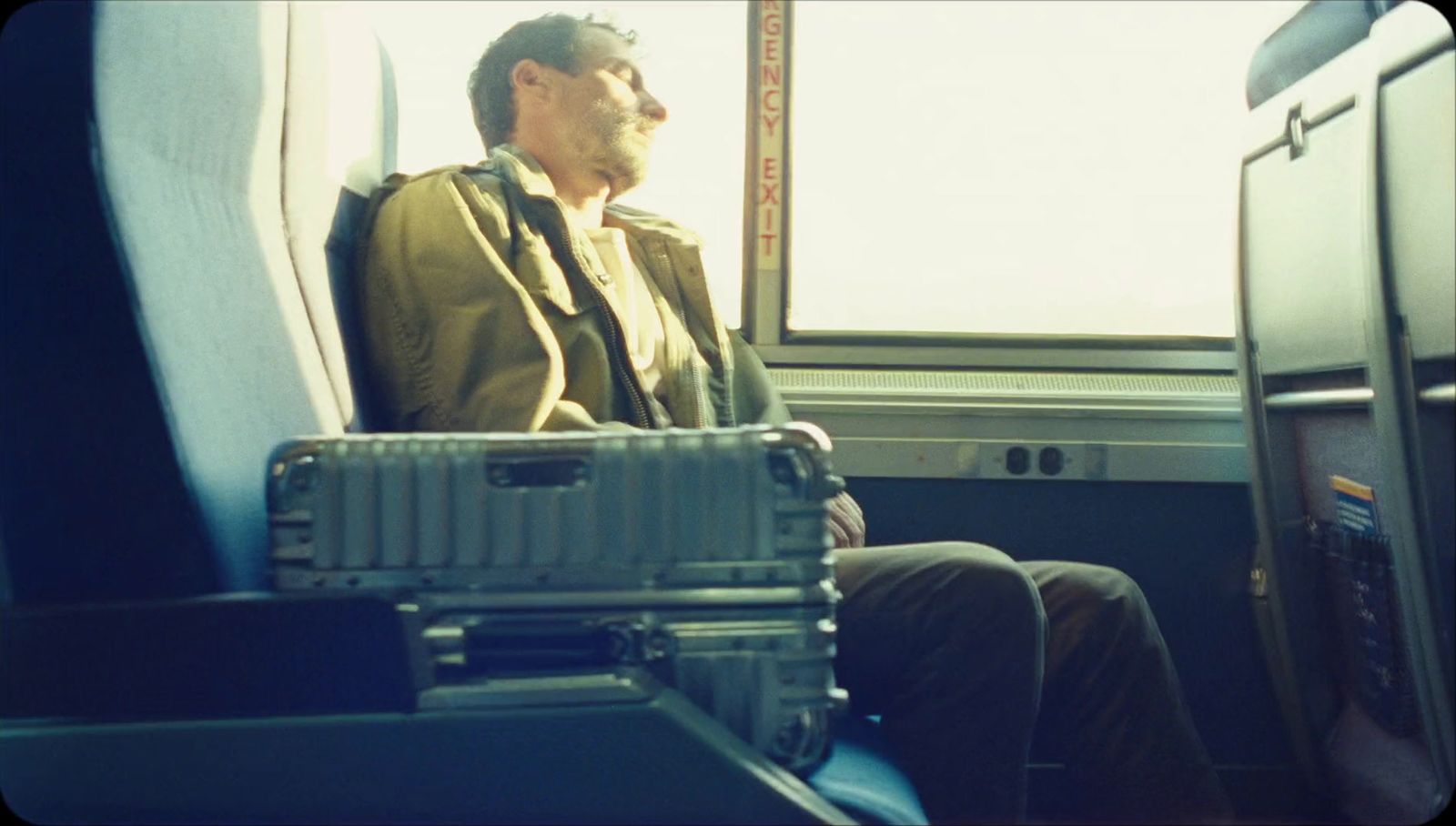 a man sitting on a train next to a window