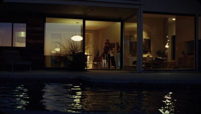 two people standing outside of a house at night