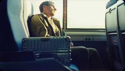 a man sitting on a train next to a window