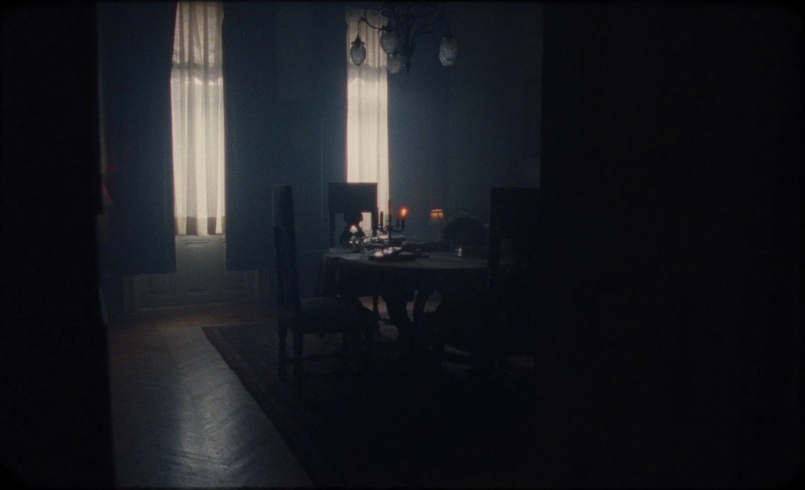 a dark room with a table and chairs