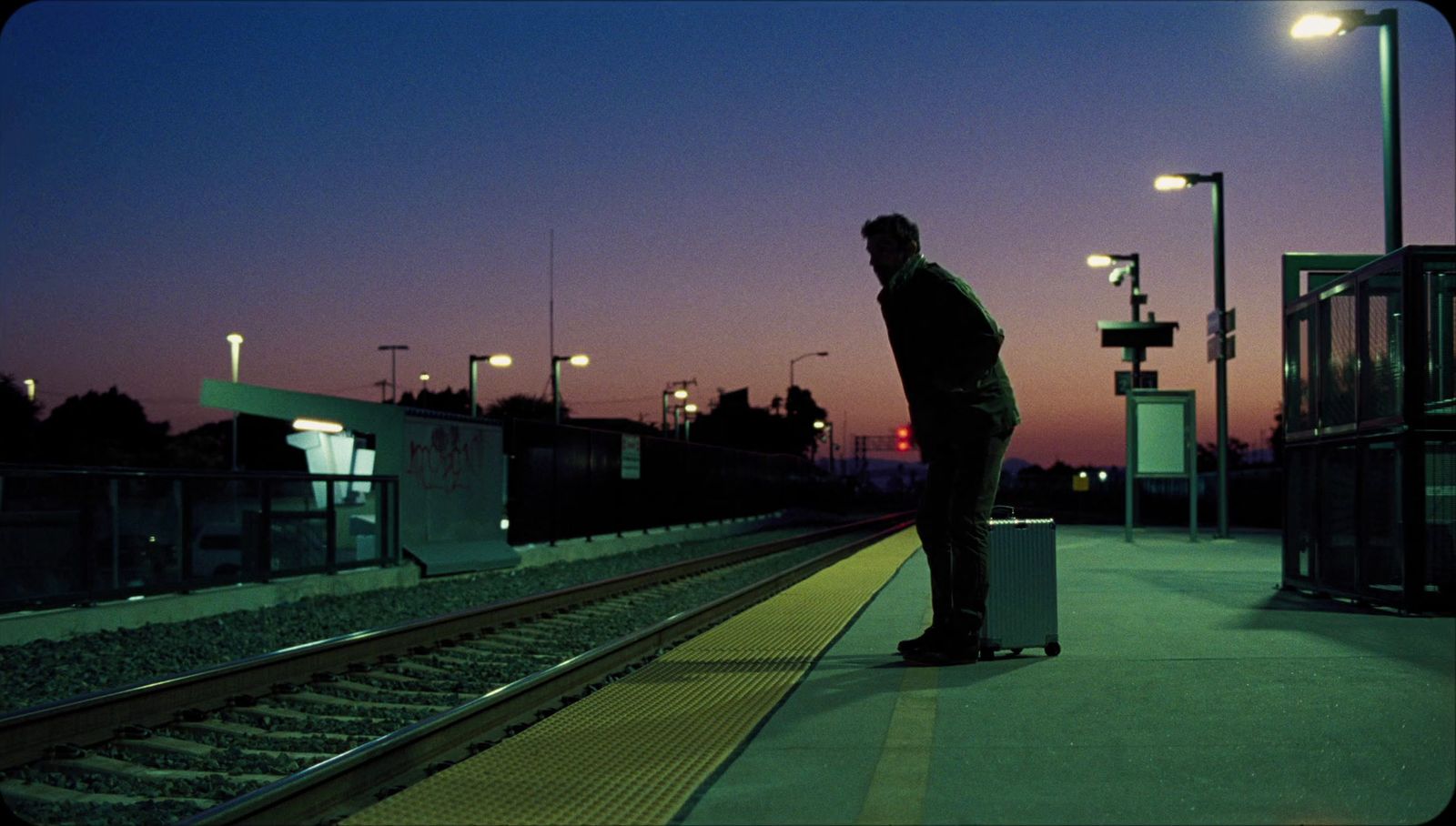 a man standing on a train platform at night