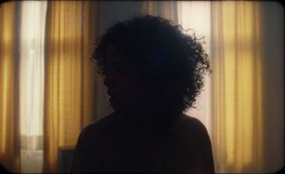 a woman with curly hair standing in front of a window