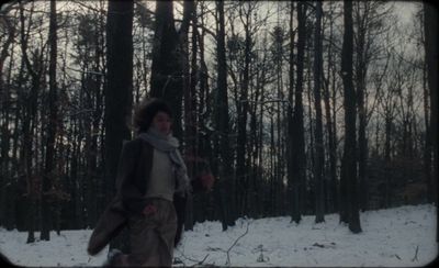 a woman is walking through the woods in the snow