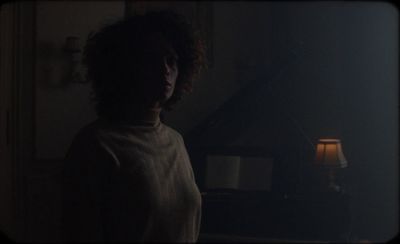 a woman standing in front of a piano in a dark room