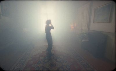 a person standing in a room with a light coming through the fog