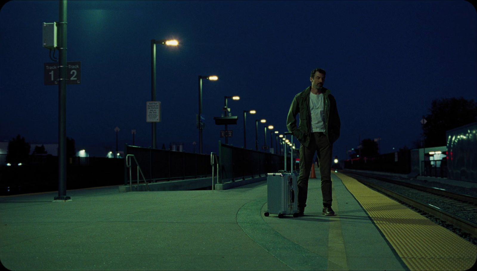 a man standing on a train platform with a suitcase