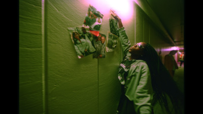 a woman standing next to a wall with pictures on it