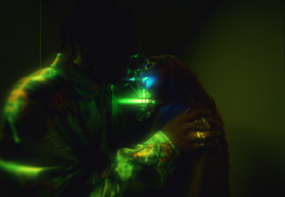 a man with dreadlocks holding a woman in a dark room