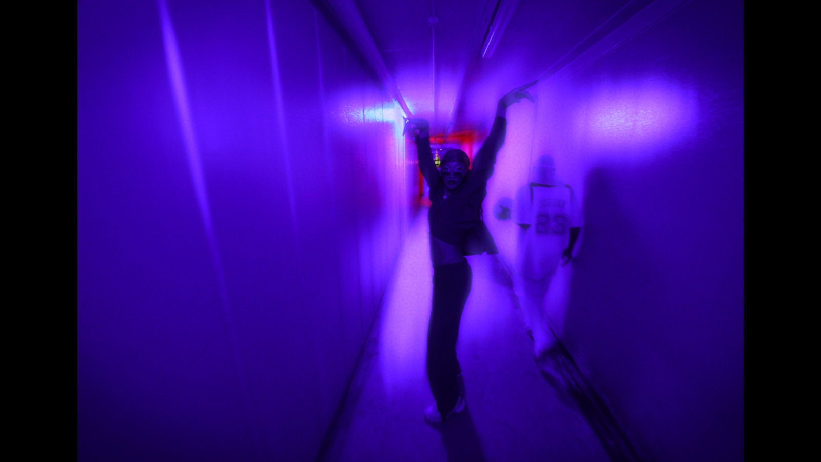 a woman standing in a purple tunnel with her arms in the air