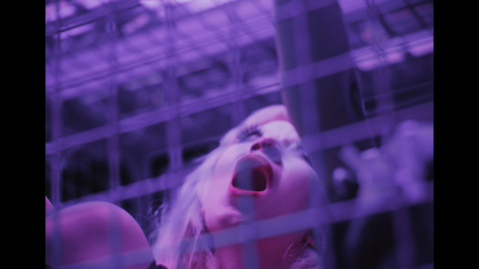 a woman with her mouth open standing behind a fence