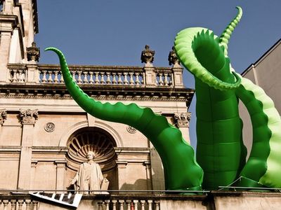 an inflatable sculpture of a giant green dragon in front of a building