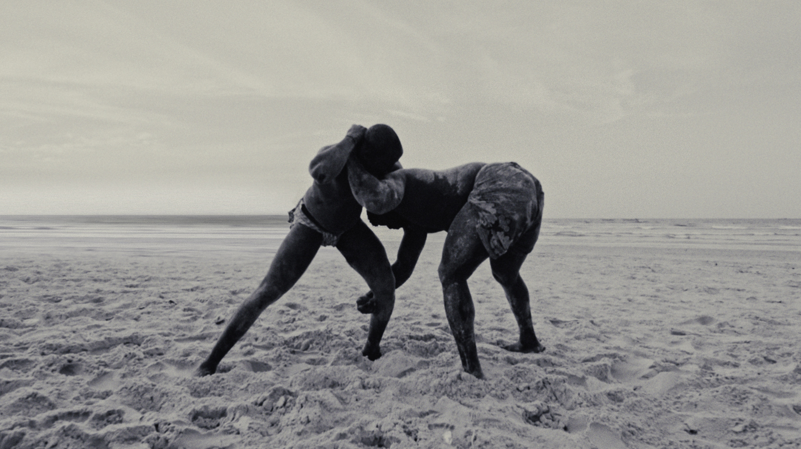 a couple of people standing on top of a sandy beach